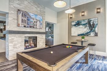 A pool table in a room with a fireplace and a painting on the wall